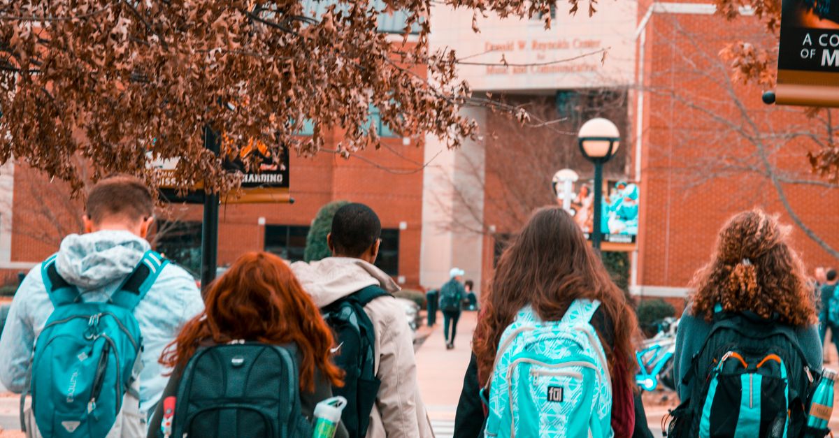 A group of college students with backpacks walking together outdoors on campus.